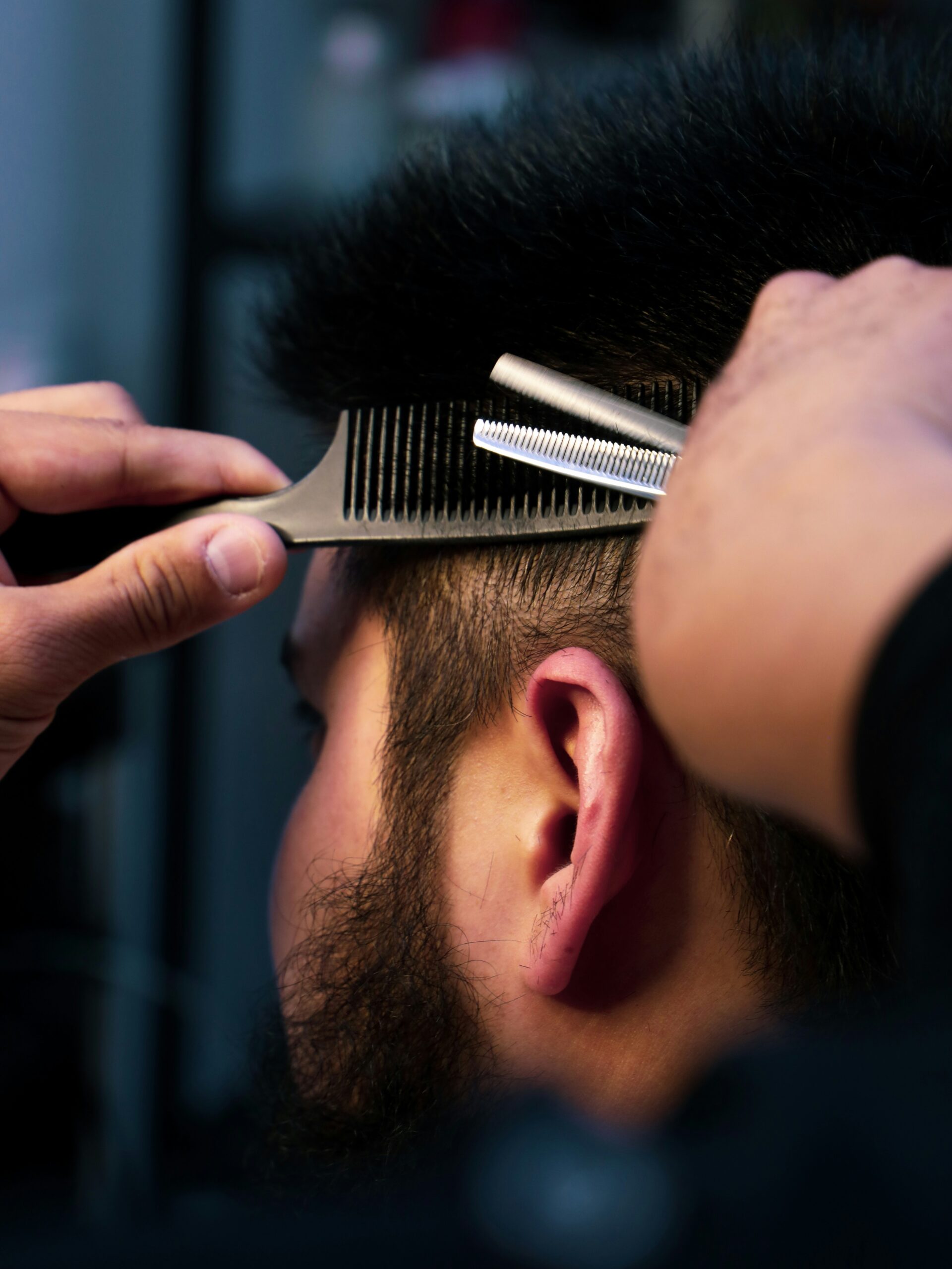 Gros plan sur un barbier en train de couper un mulet, travaillant avec précision sur les ctés.
