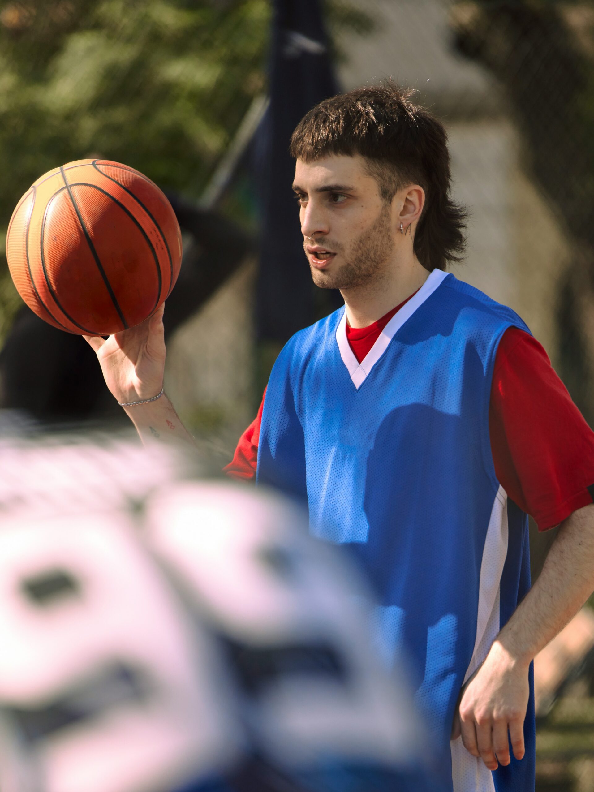 Un jeune homme avec un mulet dégradé en train de jouer au basket.