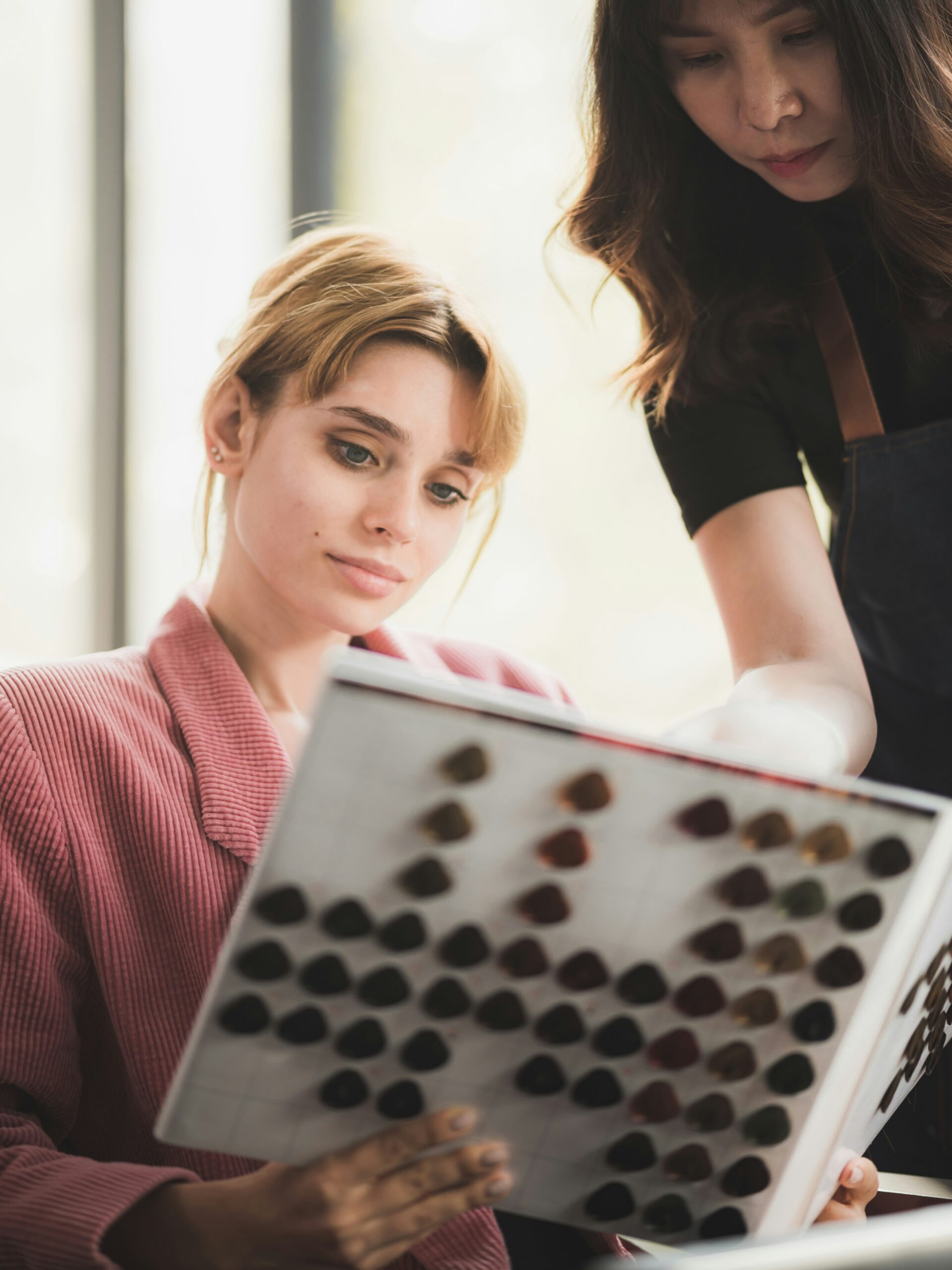 Cliente assise chez le coiffeur, consultant un nuancier de couleurs avec son coiffeur