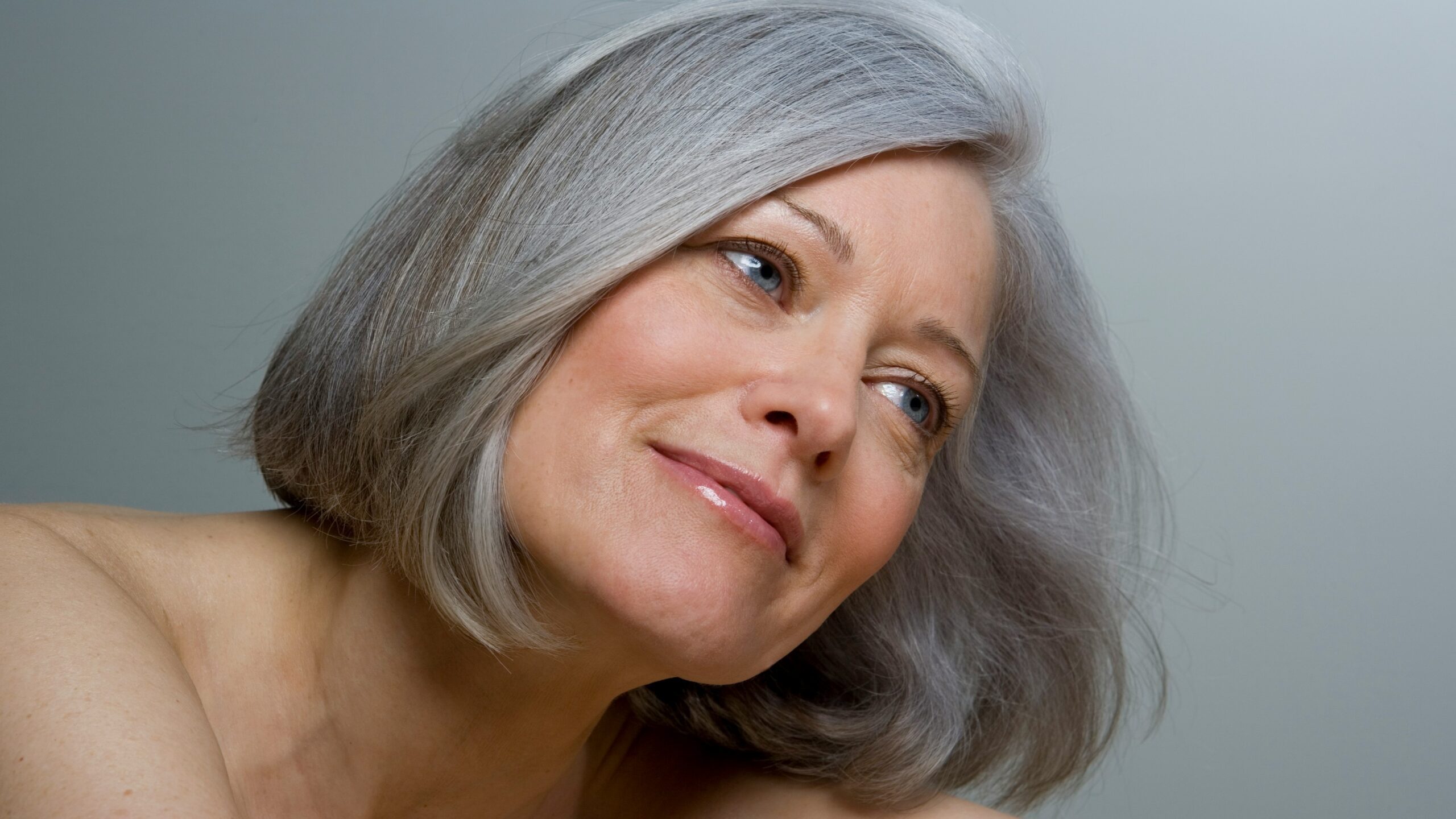 Gros plan sur une femme avec un carré gris lisse et un maquillage naturel