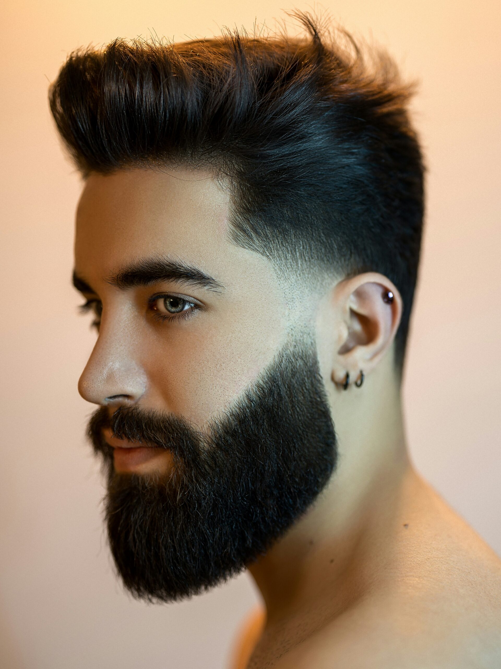 Homme au visage ovale et aux cheveux foncés portant un taper fade bas avec du volume et une barbe