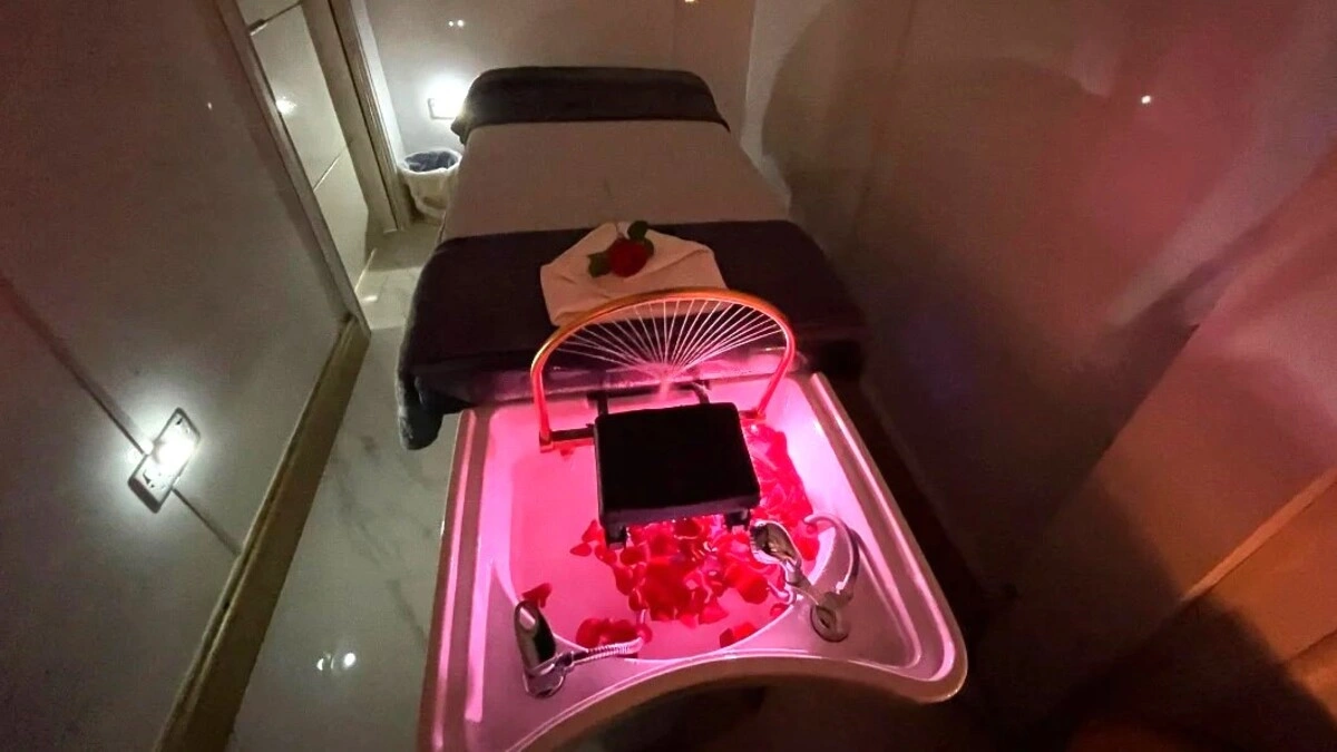 Intérieur d'une salle de head spa japonais chaleureuse à la lumière tamisée, avec une table de soin, un bac avec des pétales et du matériel de spa