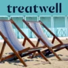 Deux chaises longues en bois rayées sur le sable devant des cabines de plage bleu pastel sur la côte de Versilia