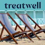 Deux chaises longues en bois rayées sur le sable devant des cabines de plage bleu pastel sur la côte de Versilia