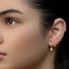 Photo en studio d'une femme arborant un curated ear avec plusieurs piercings au lobe et un anneau d'hélix