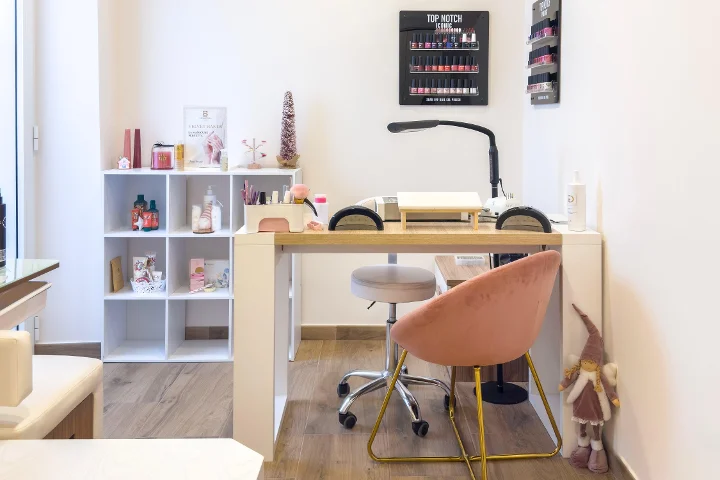 Poste de manucure chez Gd Beauty Clinc di Giulia Delogu à Alghero, avec fauteuil en velours rose et présentoir Top Notch de vernis à ongles.