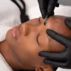 Gros plan d'une esthéticienne réalisant un dermaplaning sur une cliente en institut