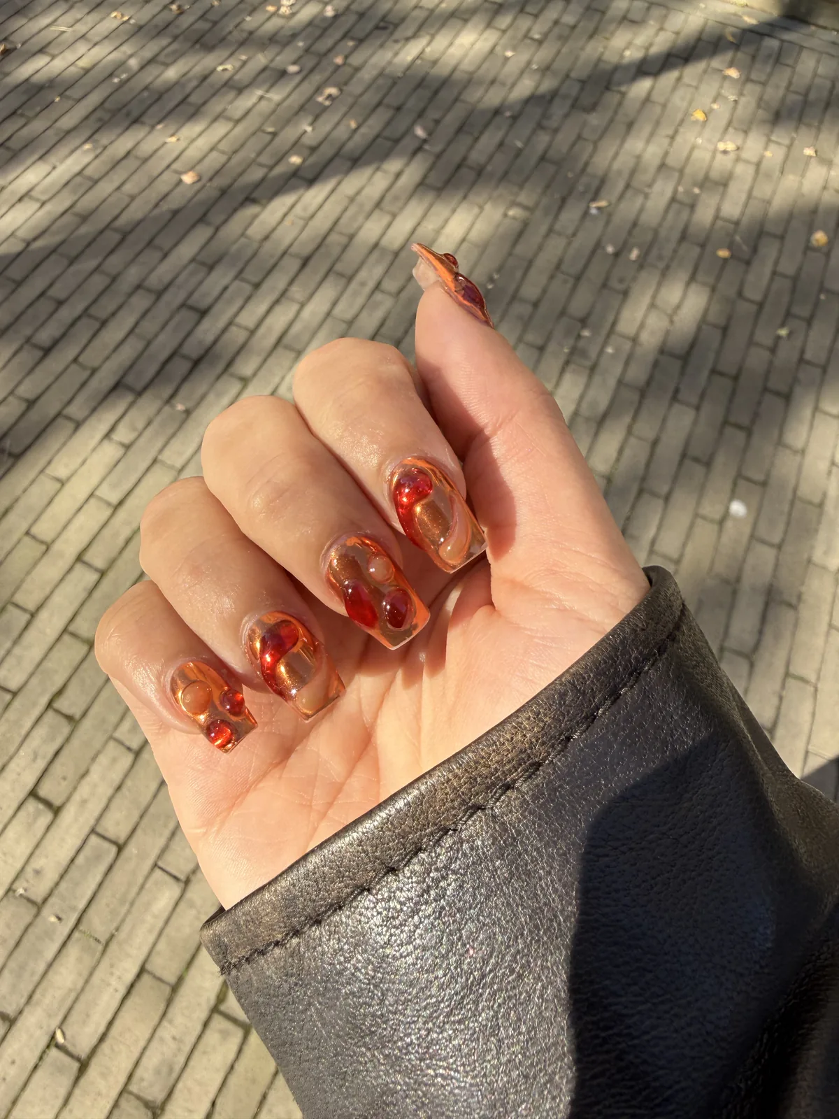 Nail art lava nails aux volutes ambrées et rouges sur base transparente